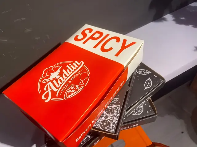 A red spicy box stacked on black Aladdin pizza boxes.