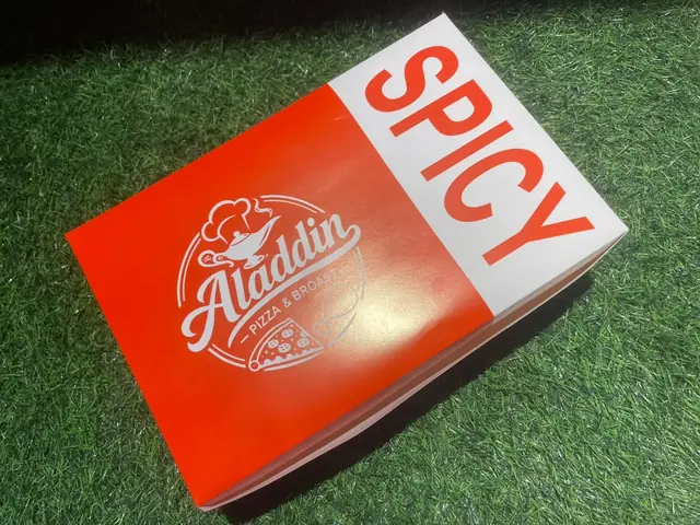 Red Aladdin spicy takeaway box on the outdoor grass.